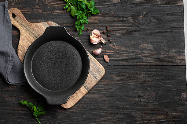 istock Empty black cast iron pan with herbs and garlic on wooden background 2238114850