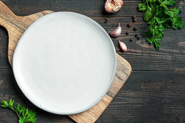 istock Empty white plate with herbs and garlic on wooden background 2238114951