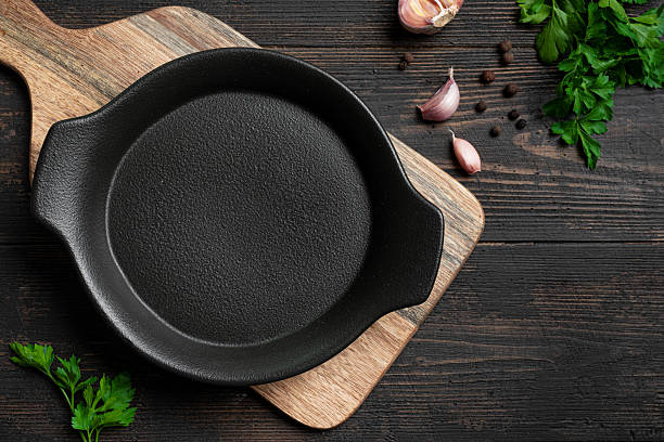 istock Empty black cast iron pan with herbs and garlic on wooden background 2238115063
