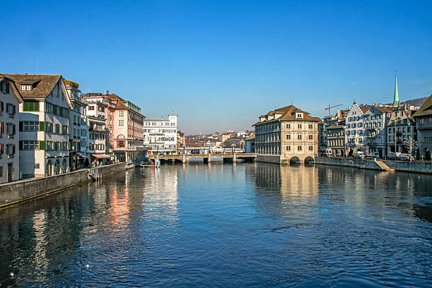 A picturesque view of central Zurich, featuring historic architecture and the river's reflection on a sunny day. A tourist destination in Switzerland.