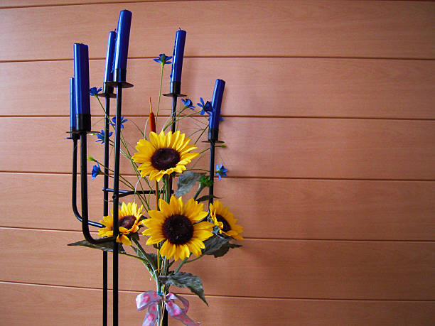Decoration made of a metal floor candlestick with several blue candles and a sunflowers