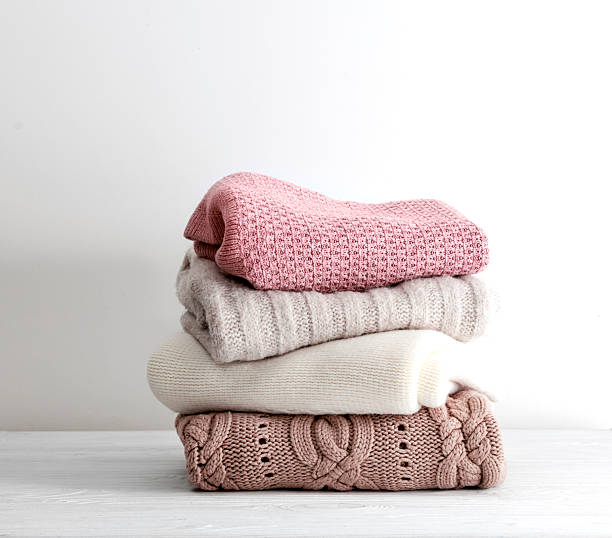 istock Stack of knitted clothes,folded sweaters pile on empty space background.Winter knits heap on table , nobody. 2238119861