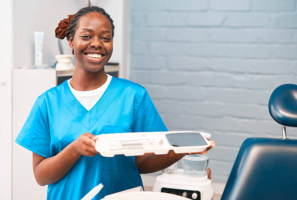 istock Friendly Dental Assistant In Blue Scrubs Holds Tray With Tools In Modern Dentistry Office 2238120122