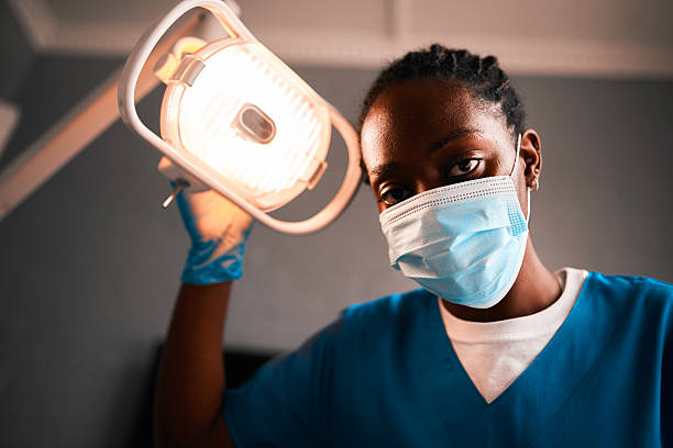 istock Dental Professional Wearing Mask Adjusts Overhead Light in Modern Clinic, Ready for Procedure 2238120212