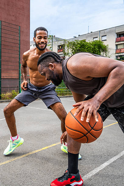 istock Medium Shot of Two Black Men Smiling while Playing Basketball 2238120250