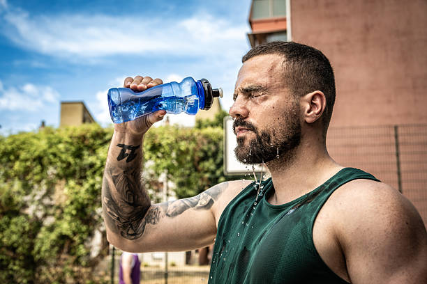 istock Bearded Man Drinking Water from Blue Bottle in Outdoor Setting 2238120284