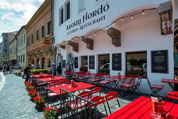 People look at the menu at a restaurant in the Buda Castle District in Budapest, Hungary, on a sunny day.