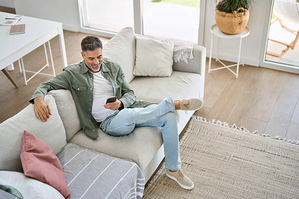 istock Relaxed middle aged man using mobile phone sitting at home on couch. Top view 2238131391