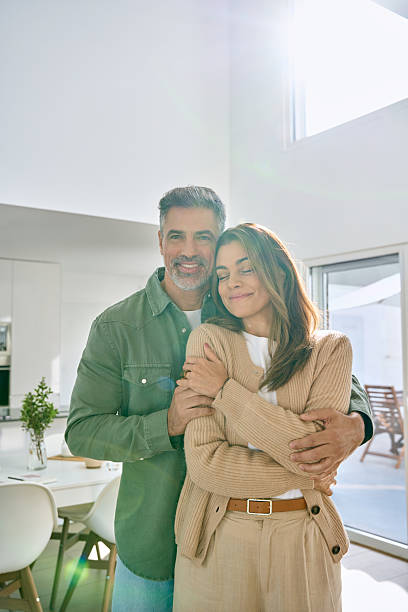 istock Happy middle aged couple hugging looking at camera standing at home. Vertical. 2238131439