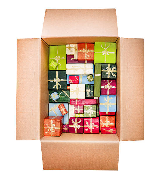 Top view of an open cardboard box containing multiple handcrafted wooden blocks painted as colorful presents with gold ribbon decorations. The vibrant assortment of red, green, blue, white, and orange gifts creates a festive and playful holiday atmosphere, ideal for Christmas concepts and celebration themes.