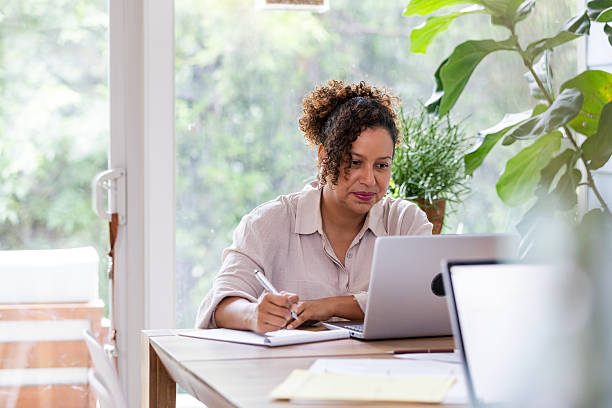 istock Woman focused on laptop, writing in notebook, working from home with plants. 2238138908