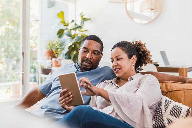 istock Couple sitting together on a sofa, engaged with a digital tablet 2238138933