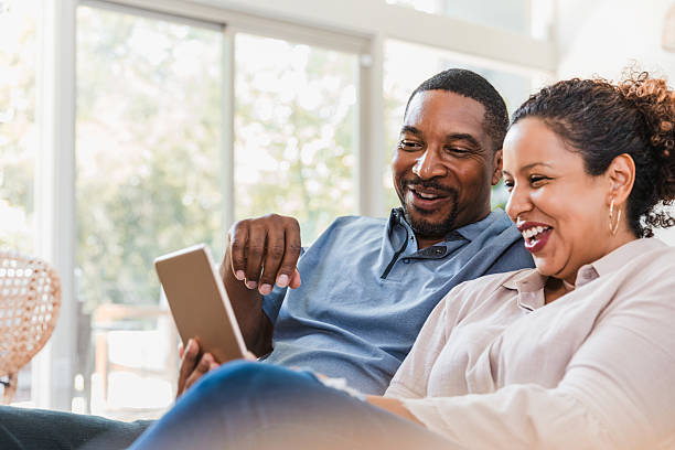 istock Couple laughs heartily while looking at a digital tablet together indoors. 2238138945
