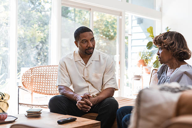 istock Two adults are sitting on a couch indoors, engaged in a conversation. 2238143506