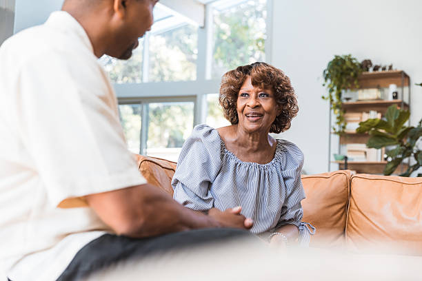 istock Joyful conversation between a senior woman and a younger man on a sofa. 2238143507