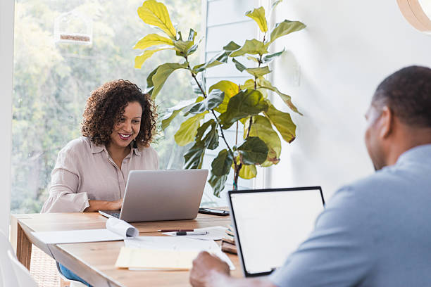 istock Two people working together on laptops, smiling and collaborating in a bright, indoor setting. 2238143541