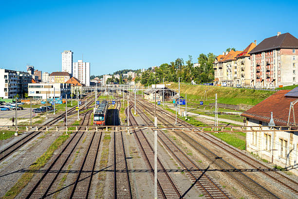 La Chaux-de-Fonds, Switzerland - September 19, 2025: A railway station with multiple tracks, a train approaching, buildings in the background, clear blue sky