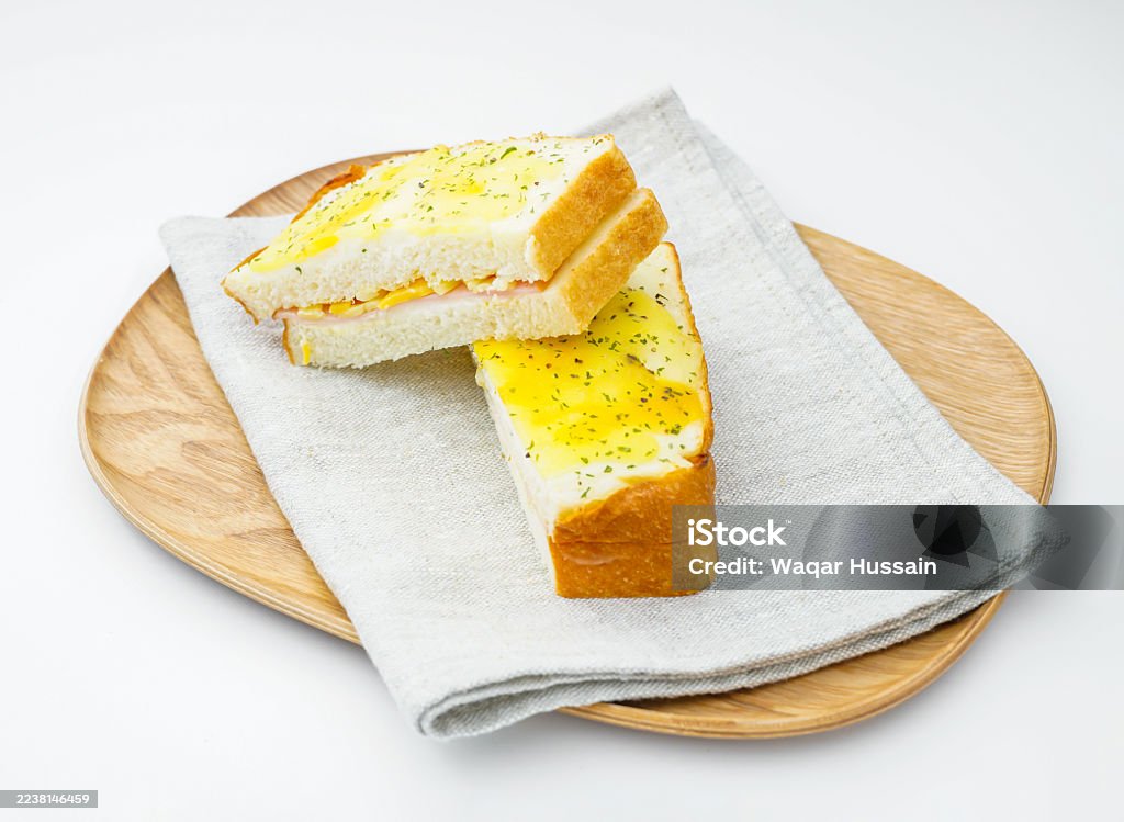 Classic Croque Monsieur Sandwich on Wooden Plate and Napkin Toasted Ham and Cheese with Egg Topping on white background side view Baked Stock Photo Classic Croque Monsieur Sandwich on Wooden Plate and Napkin Toasted Ham and Cheese with Egg Topping on white background side view Baked Stock Photo