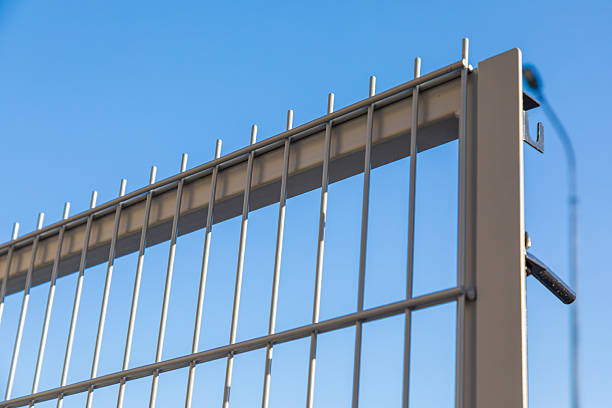istock Metal fence with vertical bars against blue sky. Protective boundary fence with vertical bars and spikes 2238148523