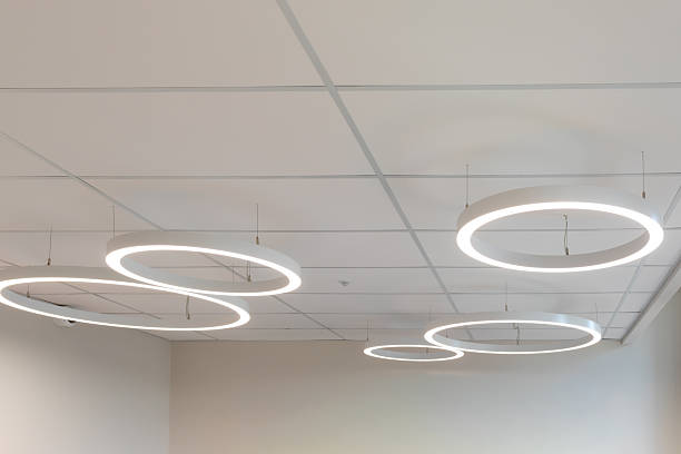 istock Sleek circular LED pendant lights suspended from a white ceiling. Minimalist lighting design for modern office or showroom. 2238148562