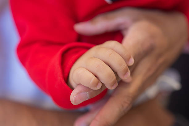Comfort, development and hand of baby in blanket closeup for growth, safety or security at home. Dreaming, resting or sleeping with infant and parent on bed in apartment nursery for morning nap