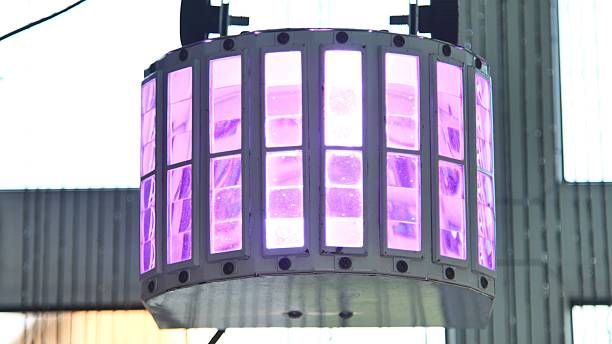 Cylindrical hanging lamp with purple light illuminating a modern space, creating a futuristic and vibrant atmosphere