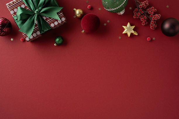 istock A festive composition featuring a wrapped gift with green ribbon and an array of Christmas ornaments and decorations on a red backdrop, evoking warm holiday cheer and seasonal greeting 2238163313