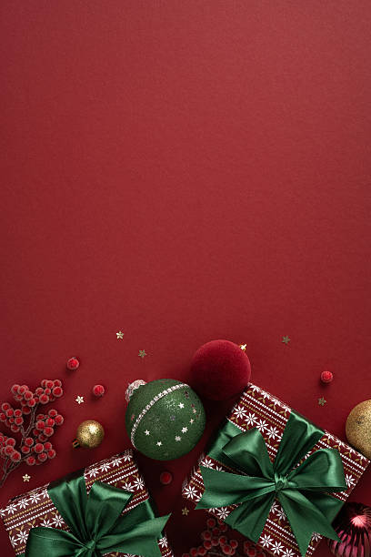 istock Colorful vertical presents with green ribbons sit on a red backdrop with ornaments, creating a warm, festive mood for Christmas and New Year celebrations 2238163322