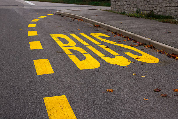 Bus stop sign in yellow letter on the road.