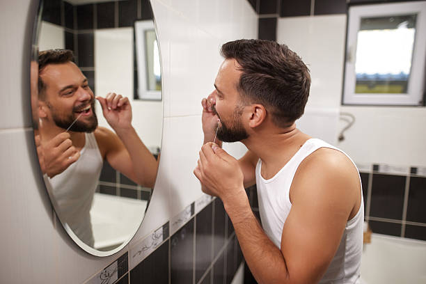 istock Man flossing teeth in bathroom mirror during morning routine 2238172677