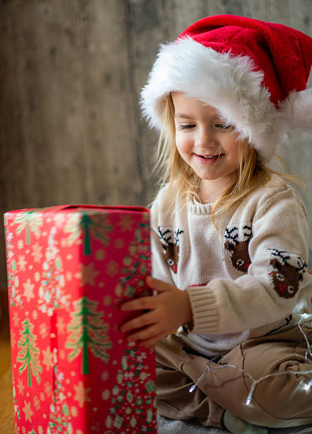 istock Young girl in santa hat unwrapping a festive gift 2238177657