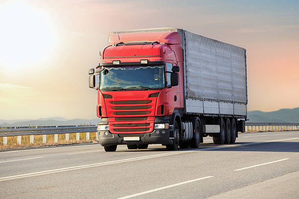 istock Red Big Truck Drives Sunlit Road 2238178133