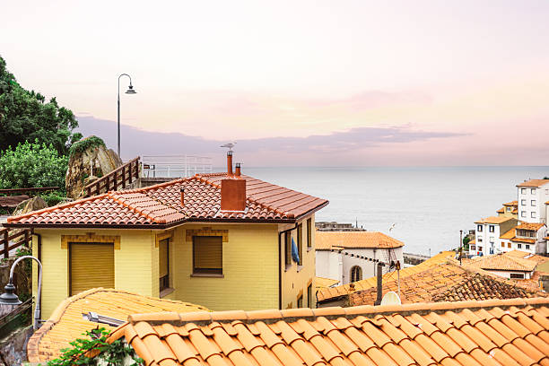 Scenic coastal view of Cudillero, Asturias, with traditional houses featuring terracotta tiled roofs overlooking the calm sea under a pastel evening sky at sunset