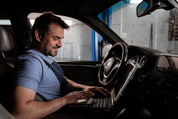 istock Mechanic works on laptop inside car at garage during the day 2238182007