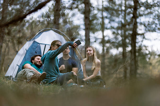 istock Friends enjoy a camping trip in a serene forest setting while sharing stories by their tent during a sunny afternoon 2238188121