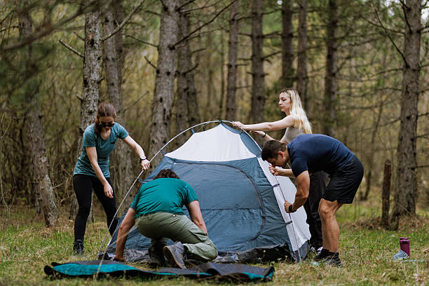 istock Individuals set up a camping tent in a serene forest during a clear afternoon, working together to secure the structure for their outdoor experience 2238188123
