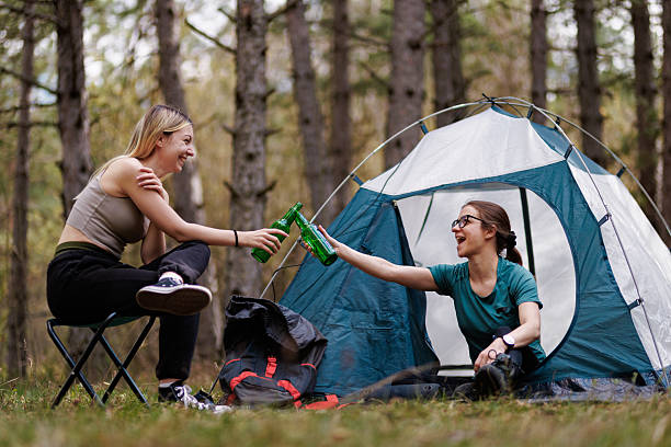 istock Friends enjoy a fun camping experience in the woods while sharing refreshments and relaxing outside their tent 2238188155