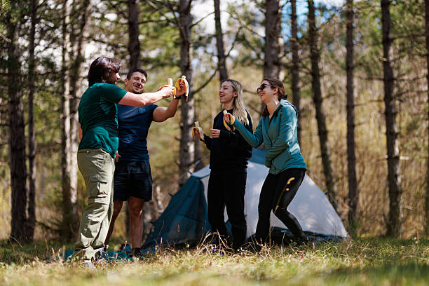 istock Friends enjoying a cheerful moment around a campsite while sharing snacks in a peaceful forest setting during the daytime 2238188215
