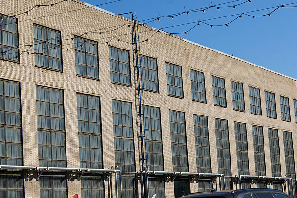 An Industrial Building Featuring Large Windows Set Against a Clear Blue Sky Above It