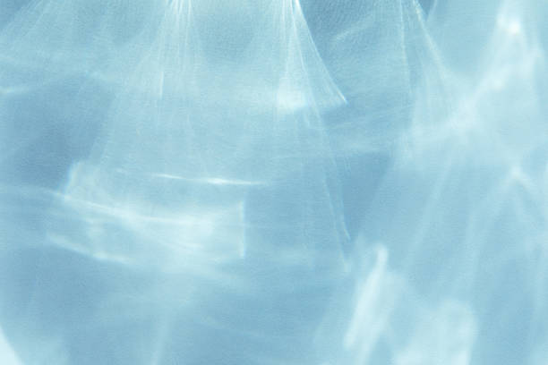 Abstract shadows blue background from pouring sunlight from glass. Natural caustic background from light glare and shine reflection effects for product presentation.