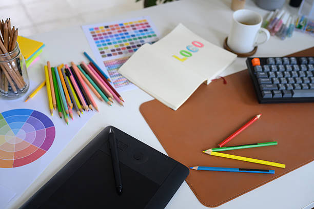 Creative graphic designer workspace with digital drawing tablet, color palette, and notebook for logo design.