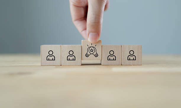 istock Creative idea generation, creative thinking at the workplace concept. Wooden block featuring a light bulb with a star among team icons, symbolizing innovation, idea generation and creative thinking. 2238216084