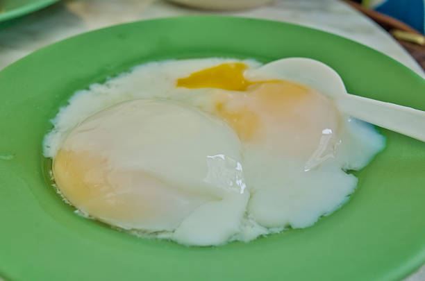 Perfectly cooked soft-boiled eggs served on a green plate with hot coffee or cocoa, toast or crackers are a popular Asian breakfast.