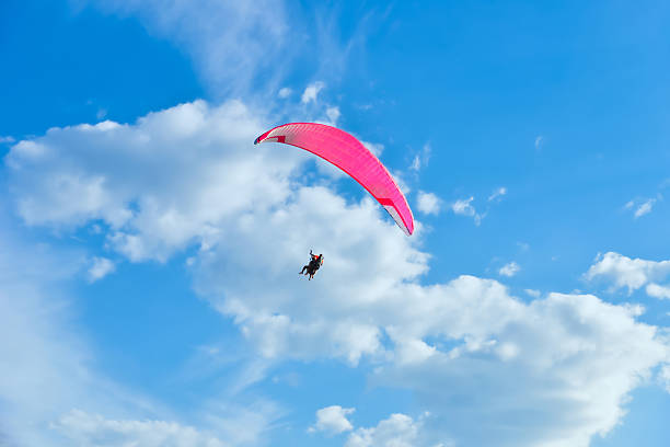 Tandem paraglider flying high against the cloudy blue sky. Copy space. Concept of sport and recreation.
