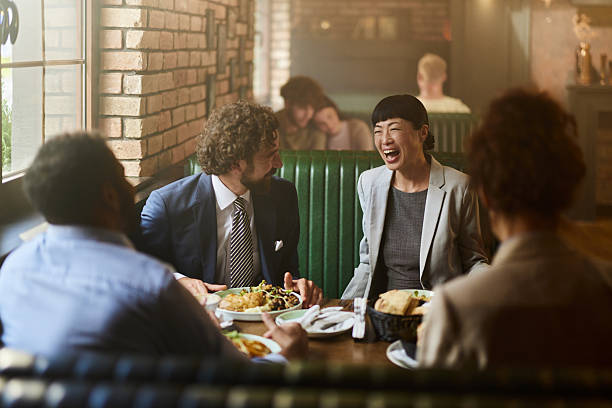 Team of cheerful entrepreneurs communicating while having brunch on a break in a restaurant.