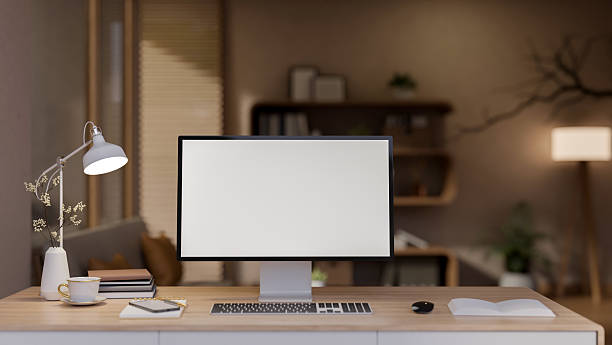 istock White screen computer and coffee cup and books aside on wooden table under lamp light in living room 2238226277
