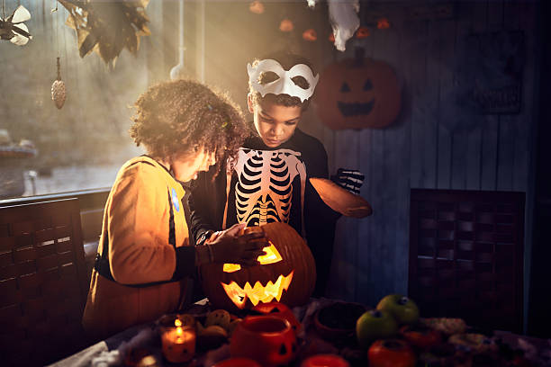 istock Shocked black siblings looking inside of Jack O' Lantern at home. 2238231792