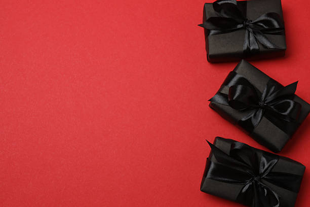 istock black gift boxes with black ribbons on a red background 2238232029