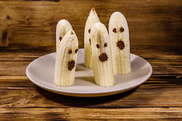 istock Scary banana ghosts in ceramic plate on a wooden table. Halloween concept 2238232280