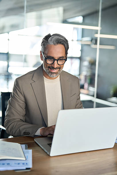 istock Smiling middle aged business man executive sitting at desk using laptop. 2238235764